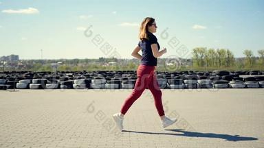 一位身材苗<strong>条</strong>的年轻女子在折叠汽车车轮的背景下穿过广场。 早上慢跑<strong>活动</strong>